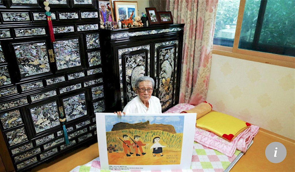 Kim Bok-dong poses with a copy of her painting, The Day A 14-year-old Girl Is Stolen Away, in 2015