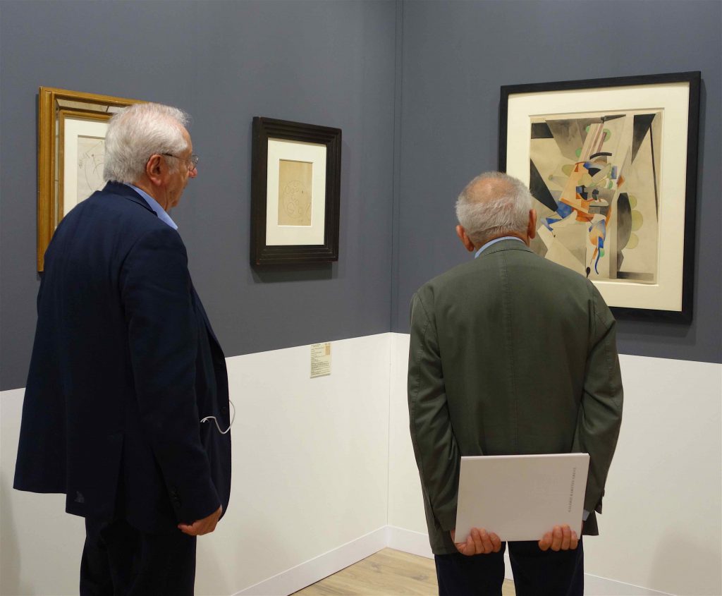 Marcel Fleiss owner of Galerie 1900 – 2000 (left) explaining Francis Picabia “En badinant” 1914, Gouache sur paper, 65 x 53.7 cm