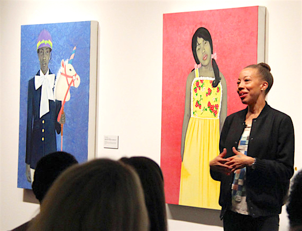 Amy Sherald lecturing in front of her paintings