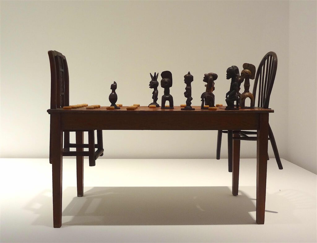 Chen Zhen “Couldn’t Bananas Be Black” 1999, Wood, chairs, African statuettes, Chinese chess