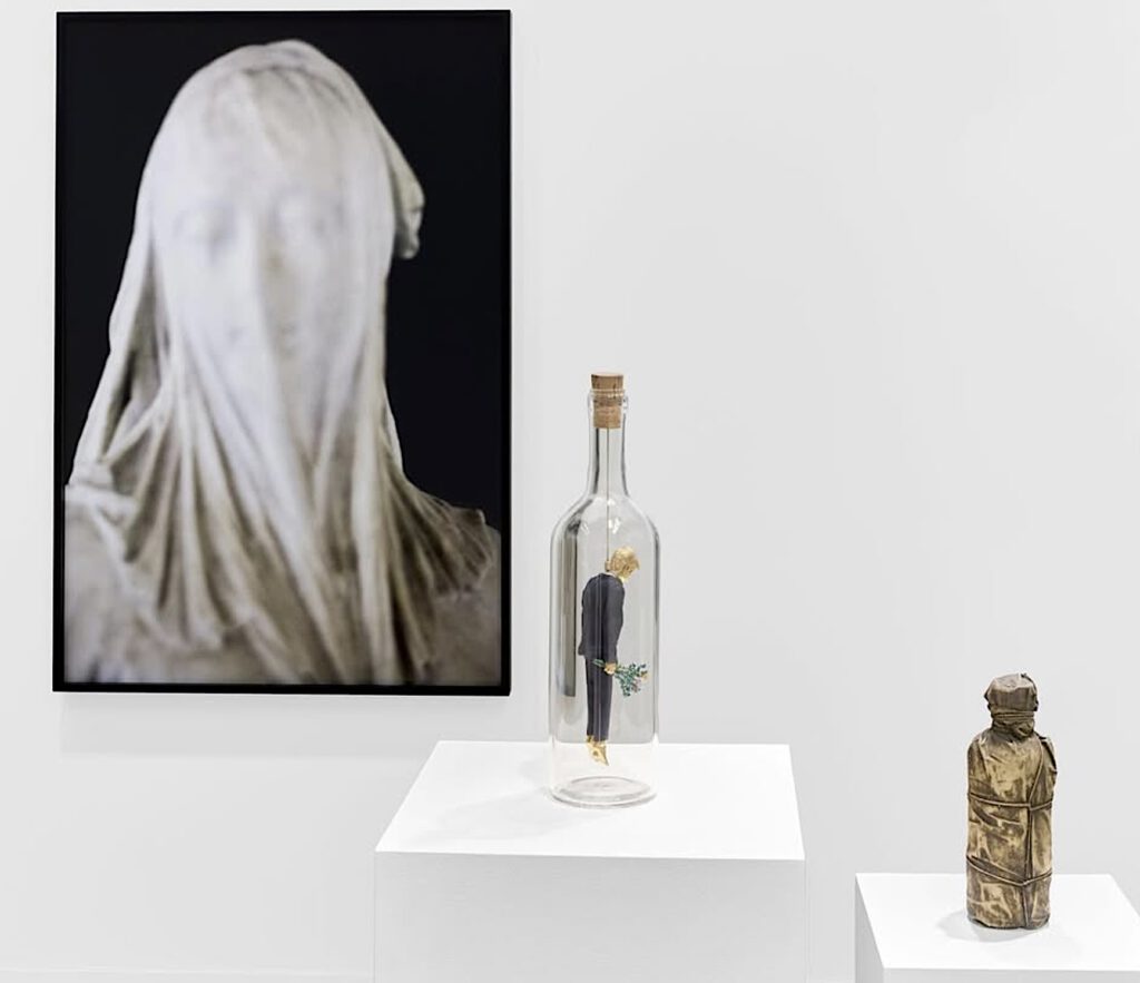 From left Nan Goldin “Veiled woman” 2024, Maurizio Cattelan “Lie” 2025, Christo “Wrapped Bottle” 1958